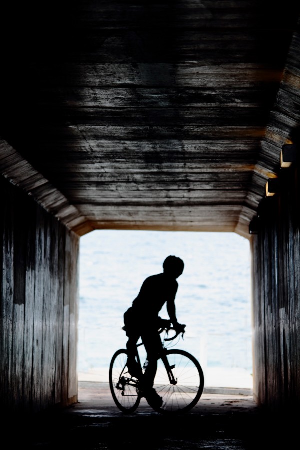 Cyclist in a tunnel silhouetted against the sea